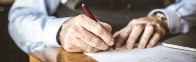 Une personne âgée signe un document avec un focus sur la main
